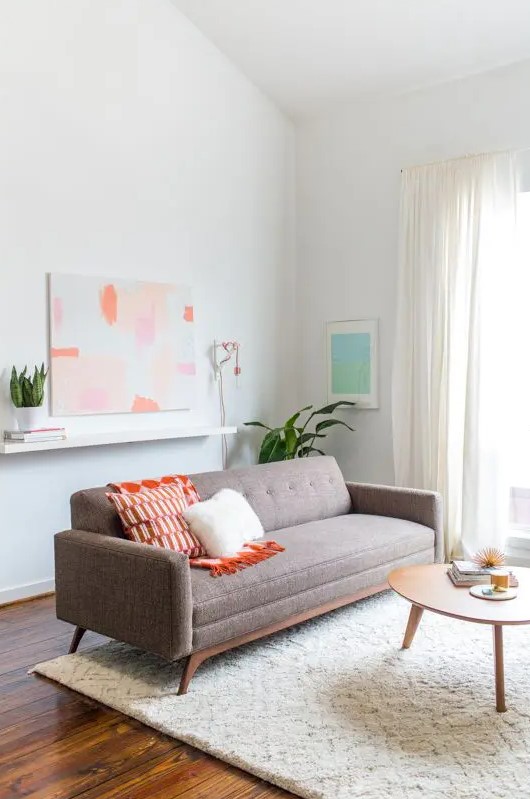 a neutral mid-century modern living room with a ledge, a grey sofa with bright pillows, a wooden coffee table and potted plants is amazing