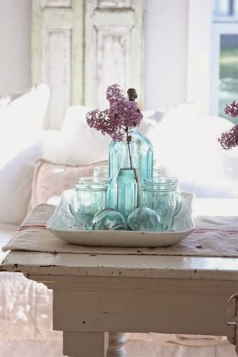 a pretty coastal centerpiece composed of a porcelain tray, light blue vintage bottles and jars and buoys is a cool idea and it's easy to realize