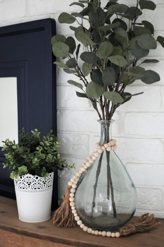 a pretty decoration of a vintage bottle, with green branches and wooden beads brings a lively feel to the space