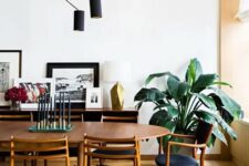 a pretty mid-century modern dining room with a stained dining table, navy chairs, a sideboard with a gallery wall and a black chandelier