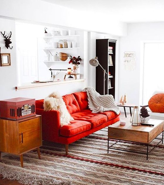 a pretty mid-century modern living room done in neutrals and spruced up with bold touches - a red sofa, a chest and an orange pillow