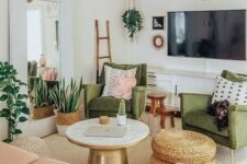 a pretty mid-century modern living room with green chairs, a blush loveseat, a round table and woven poufs, potted plants and lights