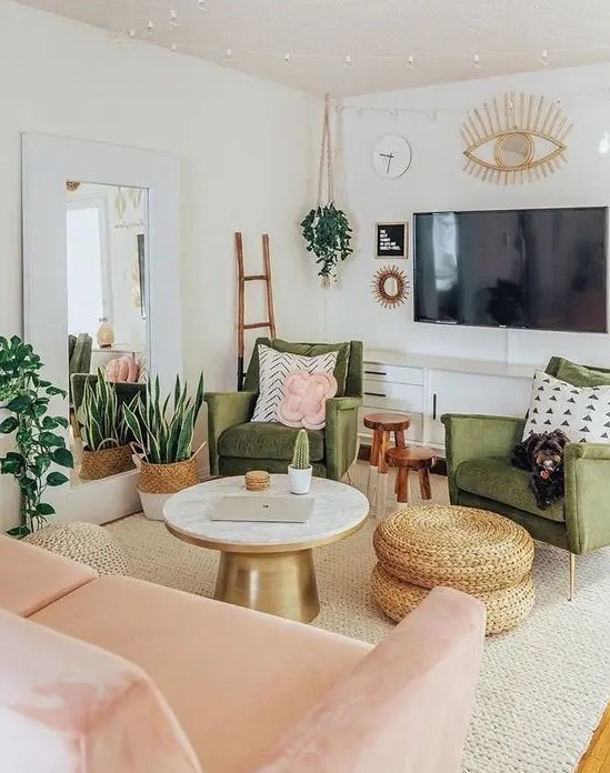 a pretty mid century modern living room with green chairs, a blush loveseat, a round table and woven poufs, potted plants and lights