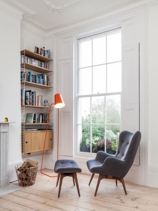 a retro-inspired grey wingback chair with a matching footrest and touches of orange plus a bold orange lamp
