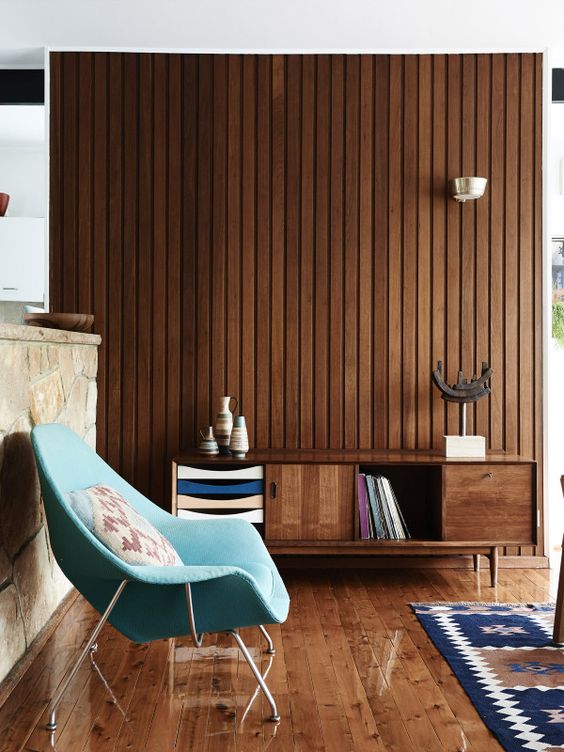 a rich-stained mid-century modern sideboard with doors, colorful drawers and an open storage compartment that matches the stained wall