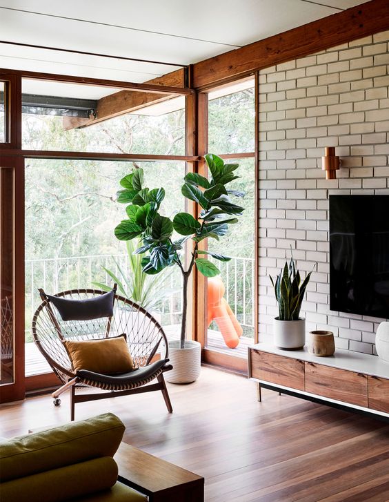 a round woven chair with an upholstered back and seat and a bright pillow is a cool mid-century modern idea