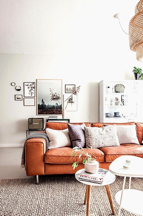 a serene Scandinavian living room with neutral furniture, a chic gallery wall and an orange leather sofa with boho pillows is amazing