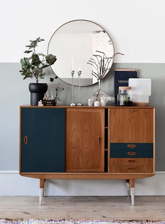 a small and cool mid-century modern sideboard in rich stain and navy, with sliding doors and drawers plus painted legs