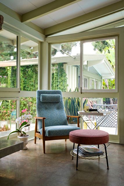 a stylish grey chair with a stained frame, legs and armrests paired with a red ottoman that doubles as a stool