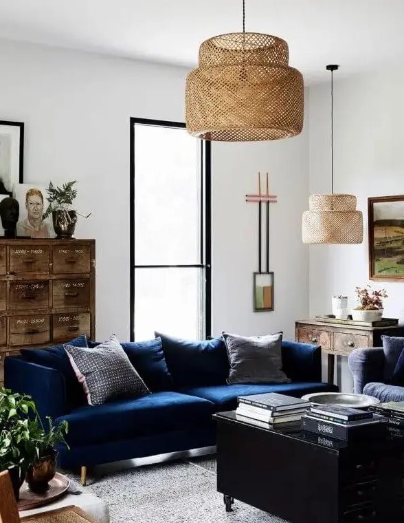 a stylish living room with a modern navy sofa, a black coffee table with drawers, a stained vintage file cabinet, some art and pendant lamps is a cool example of eclectics