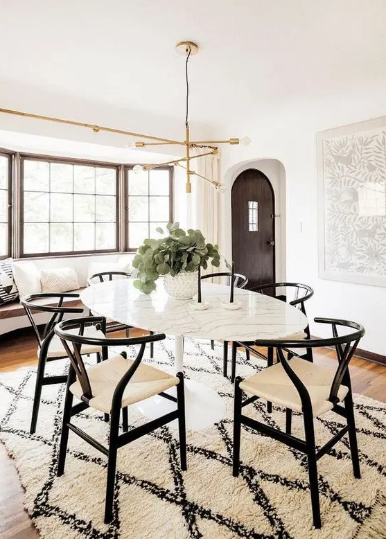 a stylish mid-century modern dining space done in black and white, with a built-in bench, an oval table, black and white chairs and a rug