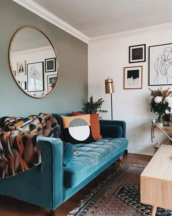 a stylish mid-century modern living room with a grey accent wall, a turquoise sofa, printed textiles and a monochromatic gallery wall