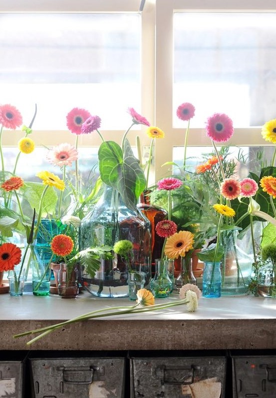 a whole arrangement of colorful bottles, jars and vases with lots of bright gerberas is a lovely summer idea