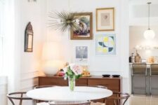 an elegant mid-century modern dining nook with a stained credenza, a round table and stained chairs, a gallery wall and a sunburst chandelier