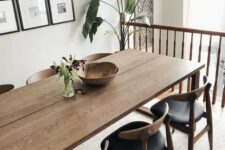 an elegant mid-century modern dining space with a stained table and black chairs, a gallery wall and a chic chandelier plus greenery here and there