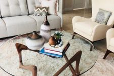 an eye-catchy mid-century modern coffee table with a round clear glass tabletop and a quirky dark stained wooden base is wow