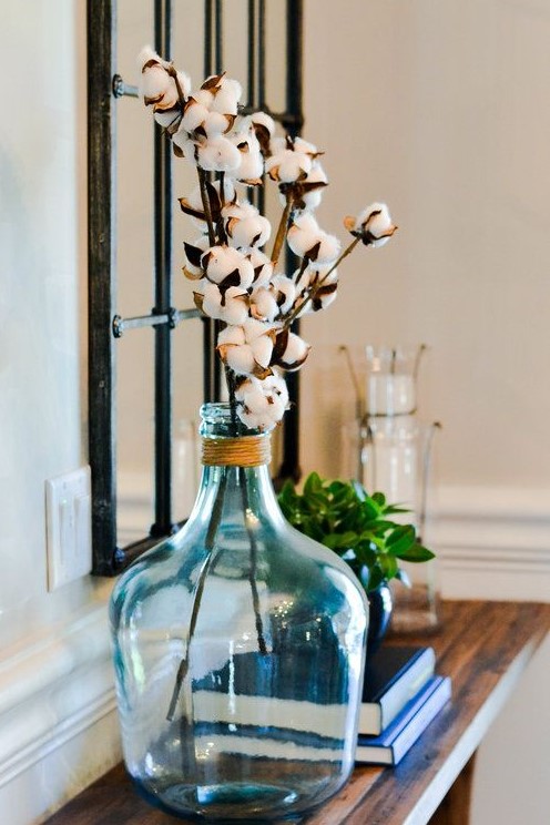an oversized blue bottle with twine and cotton branches is a cute farmhouse-inspired decoration to rock