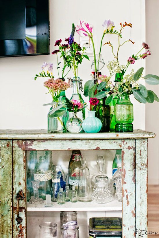 blue and green vintage bottles with super bright and colorful blooms and greenery is chic and cool decor
