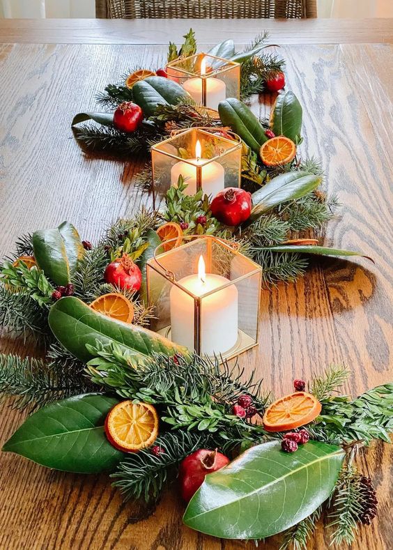 glass candleholders paired with an evergreen and foliage runner, citrus slices, cranberries and pomegranates are amazing for Christmas decor