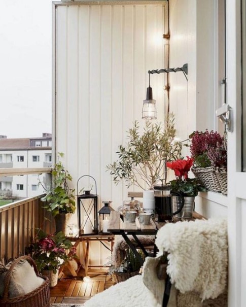 a Christmas balcony with lush bright blooms, greenery in pots, candle lanterns and faux fur here and there