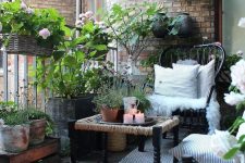 a Nordic balcony with a printed rug, a black chairs and a woven table, potted greenery, candle lanterns and candle holders is amazing
