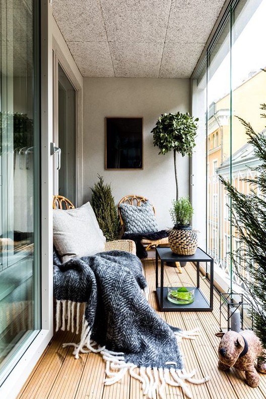 a Nordic balcony with rattan furniture, printed textiles, potted plants and candle lanterns for a chic space