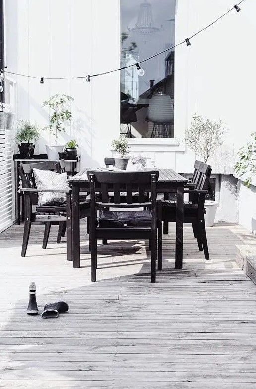 a Nordic black and white space with a simple black wood dining set, a black table and lots of potted greenery to refresh the space
