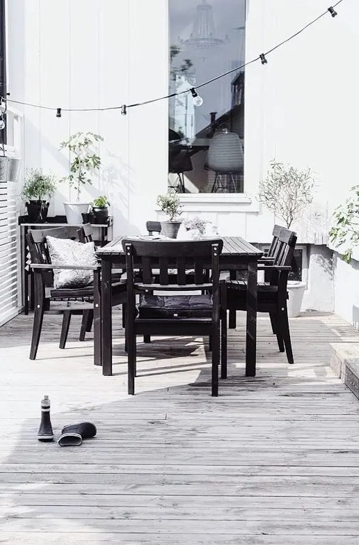 a Nordic black and white space with a simple black wood dining set, a black table and lots of potted greenery to refresh the space a Nordic black and white space with a simple black wood dining set, a black table and lots of potted greenery to refresh the space