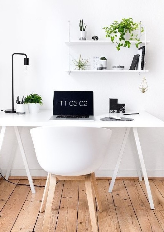 a Nordic home office in white, accented with some black touches and a black table lamp plus greenery to refresh the space