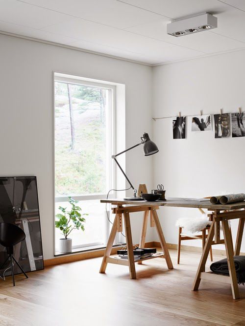a Nordic home office with a trestle desk, wooden chair, a black and white gallery wall and a large window to maximize the light