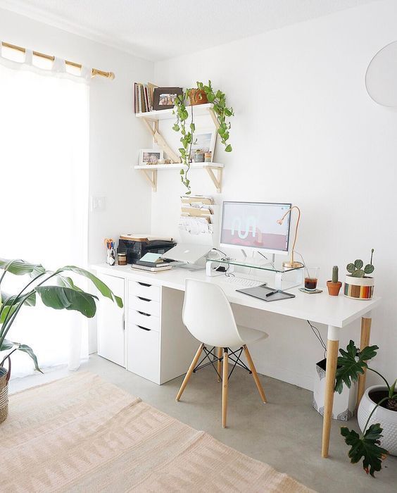a Nordic home office with a white desk, file cabinets, a white chair, wall-mounted shelves, potted plants and touches of gold