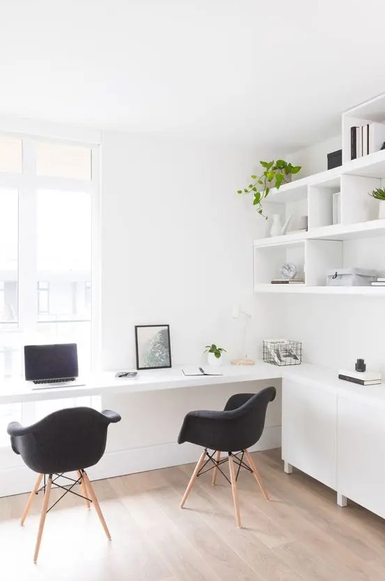 a Nordic light-filled working space with open shelves and sleek cabinets, a built-in desk and black chairs and potted greenery