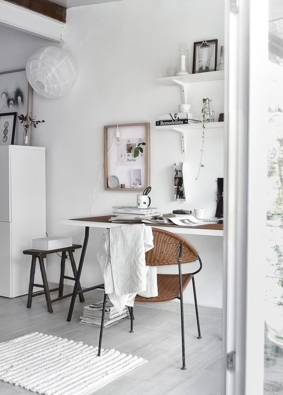 a Nordic neutral home office with a trestle desk, some wall-mounted shelves, a black stool and a woven rug