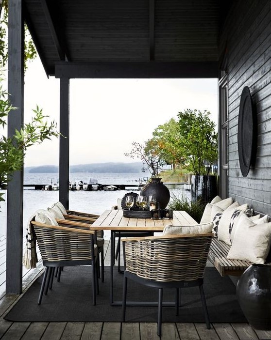 a Nordic space with wicker chairs, a wooden table and bench, lots of greenery in pots and blakc tableware a Nordic space with wicker chairs, a wooden table and bench, lots of greenery in pots and blakc tableware