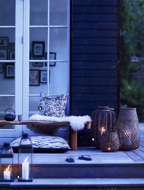 a Nordic summer terrace in black and white, with a bench, faux fur, pillows, wicker and glass candle holders a Nordic summer terrace in black and white, with a bench, faux fur, pillows, wicker and glass candle holders