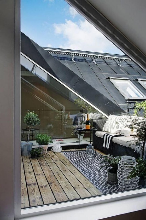 a Nordic terrace with a printed rug, a black sofa with pritned pillows, potted greenery and a small table a Nordic terrace with a printed rug, a black sofa with pritned pillows, potted greenery and a small table