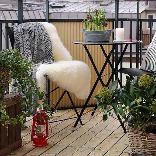 a Scandinavian balcony with black metal furniture, textural and printed textiles, crates and baskets and a red lantern is cool