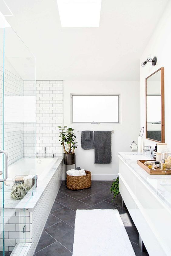 a Scandinavian bathroom with white and grey tiles, a basket for storage and potted plants