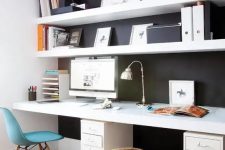 a Scandinavian home office with a black wall and white IKEA lack shelves and a white deck standing out in front of such a wall