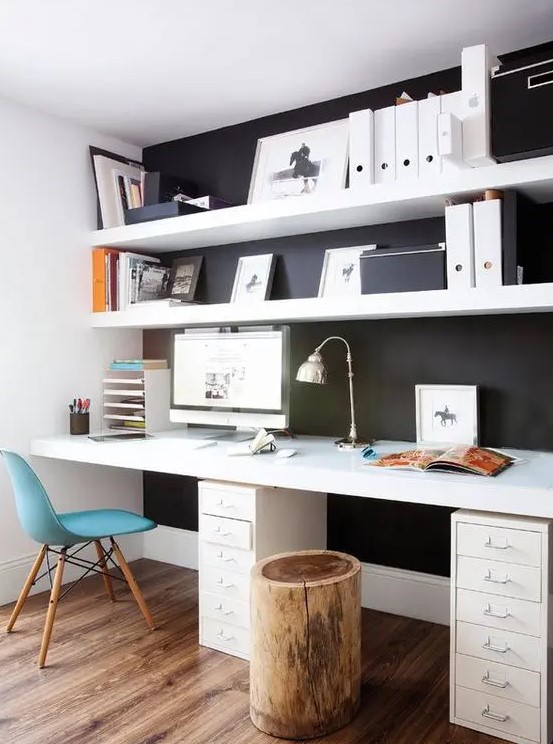 a Scandinavian home office with a black wall and white IKEA lack shelves and a white deck standing out in front of such a wall