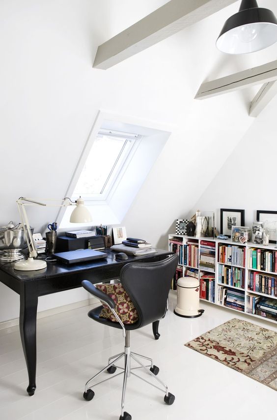 a Scandinavian home office with a bookshelf, a black vintage desk, a black chair, a table lamp, white wooden beams and black pendant lamp