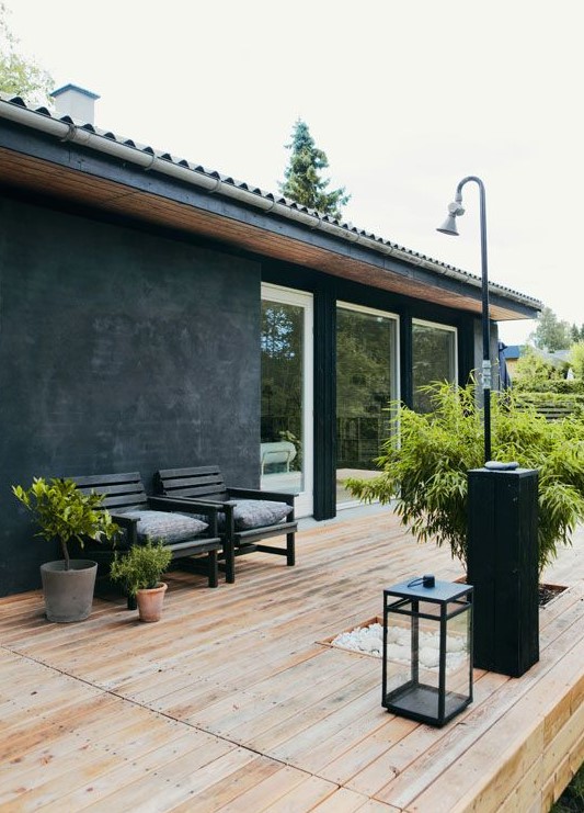 a Scandinavian terrace with black chairs, candles lanterns, a large planter and smaller ones with greenery