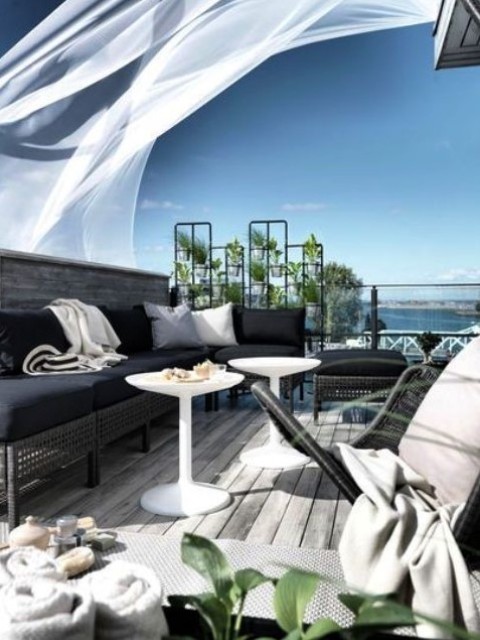 a beautiful contemporary seaside terrace with dark wicker furniture and black upholstery, white coffee tables and a chair, black and white pillows a beautiful contemporary seaside terrace with dark wicker furniture and black upholstery, white coffee tables and a chair, black and white pillows