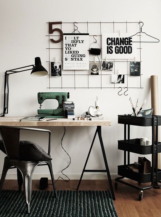 a black and white Scandinavian home office with a grid with notes, a trestle desk, an IKEA Raskog cart and lamps