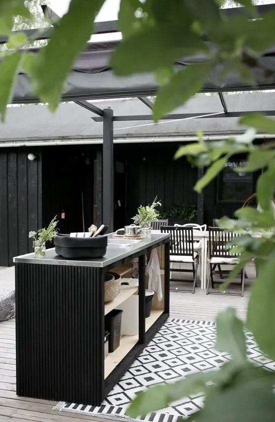 a chic Nordic outdoor space with a deck, a whitewashed dining table and black chairs, a black kitchen island a chic Nordic outdoor space with a deck, a whitewashed dining table and black chairs, a black kitchen island