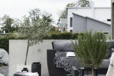 a contrasting Scandinavian terrace with black wicker furniture, a coffee table, potted greenery and jute poufs