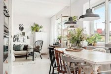 a cute Scandinavian dining space wiht a white vintage dining table, mismacthing vintage chairs, black pendant lamps and greenery
