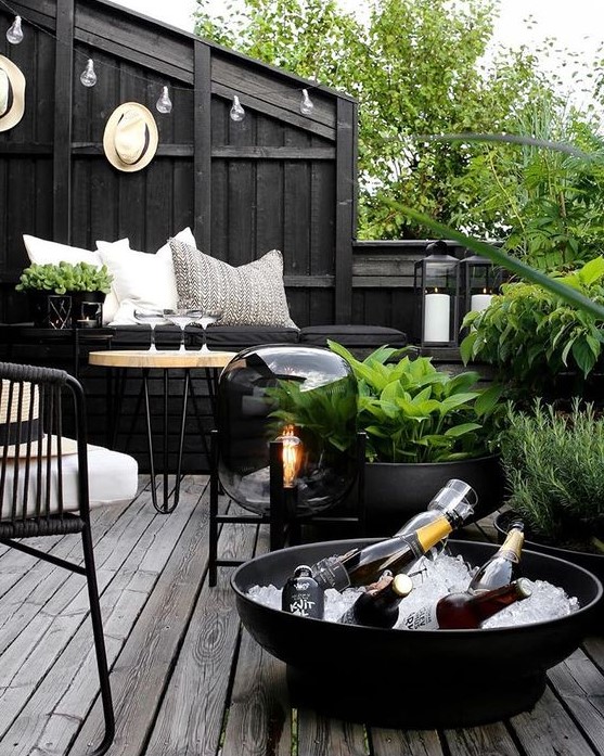 a dark Nordic terrace with blakc walls, planters and bowls, metal and wooden furniture, a catchy floor lamp and greenery that refreshes the space a dark Nordic terrace with blakc walls, planters and bowls, metal and wooden furniture, a catchy floor lamp and greenery that refreshes the space