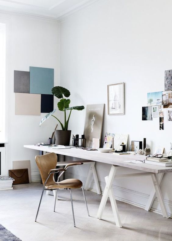 a dreamy Scandinavian home office with a large whitewashed desk, a plywood chair, a gallery wall and an artwork on the wall