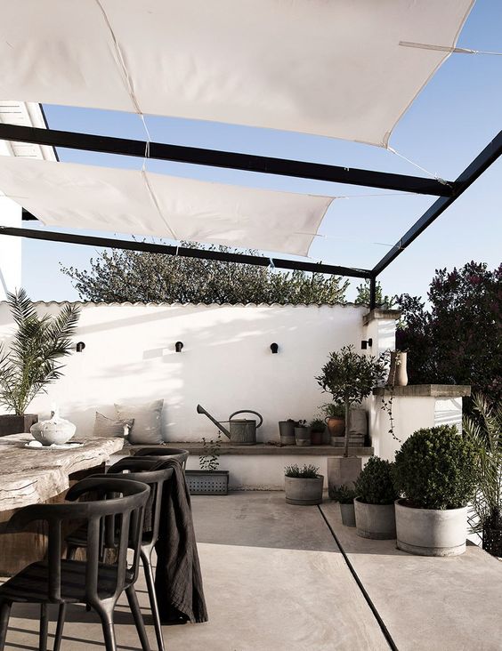 a dreamy Scandinavian terrace with a built in bench, a living edge dining table, black chairs and potted greenery a dreamy Scandinavian terrace with a built-in bench, a living edge dining table, black chairs and potted greenery